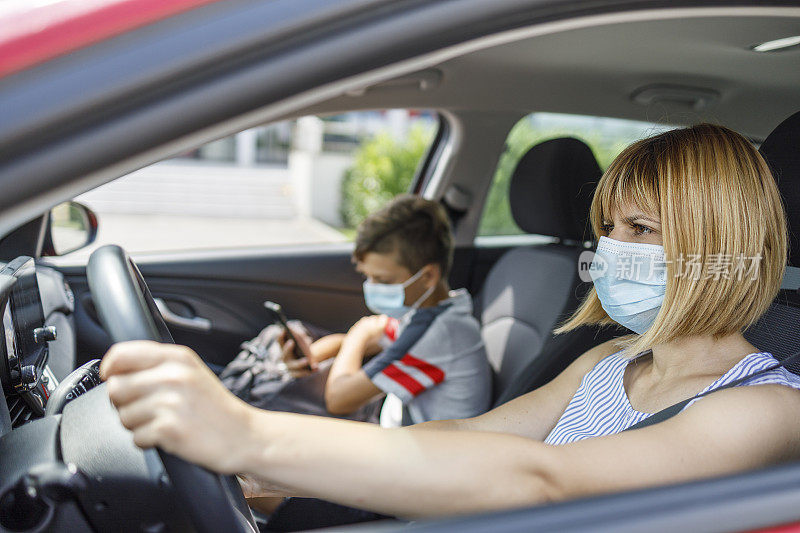 Serious woman wearing protective mask and riving her son to school